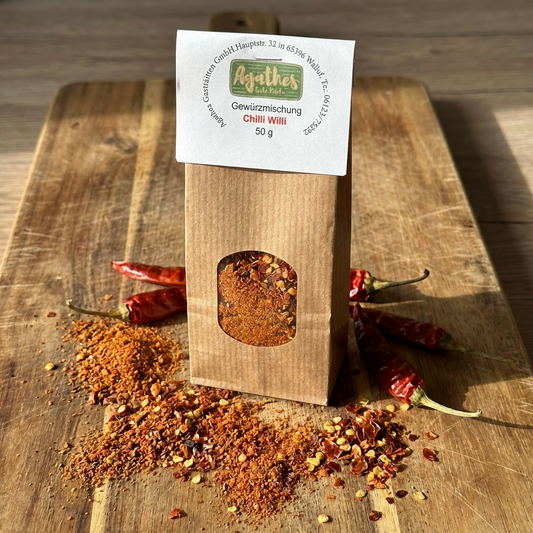 Chili Gewürz Tüte auf einem Holzbrett mit Chili Gewürz und Schoten abgebildet