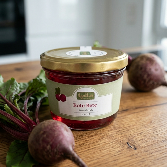 Rote Bete Brotaufstrich im Glas auf einer holzernen Arbeitsfläche mit einer Rote Bete Knolle im Bild